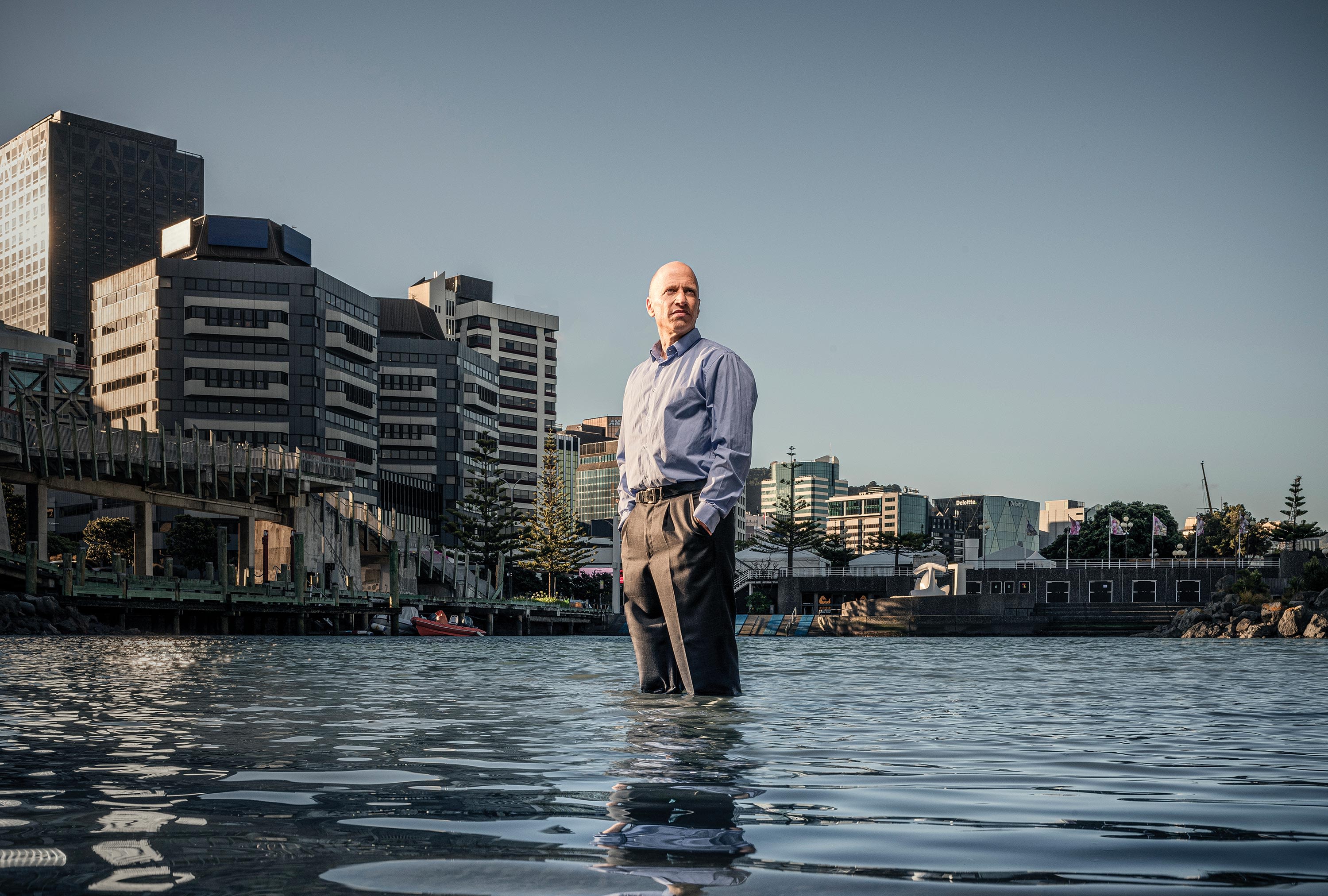 Professor Ilan Noy standing knee deep in the Wellington harbour inlet 