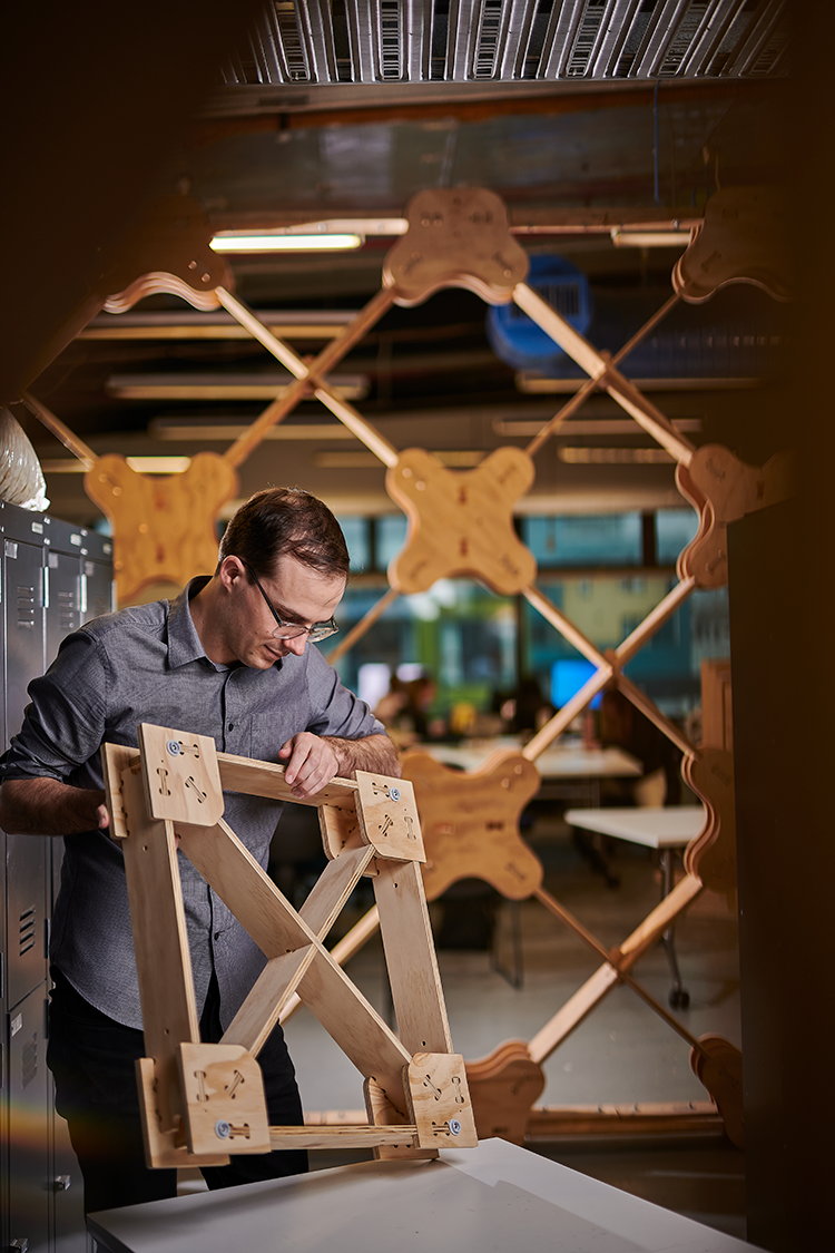 Ged Finch stood in front of wall made of XFrame inspecting XFrame piece