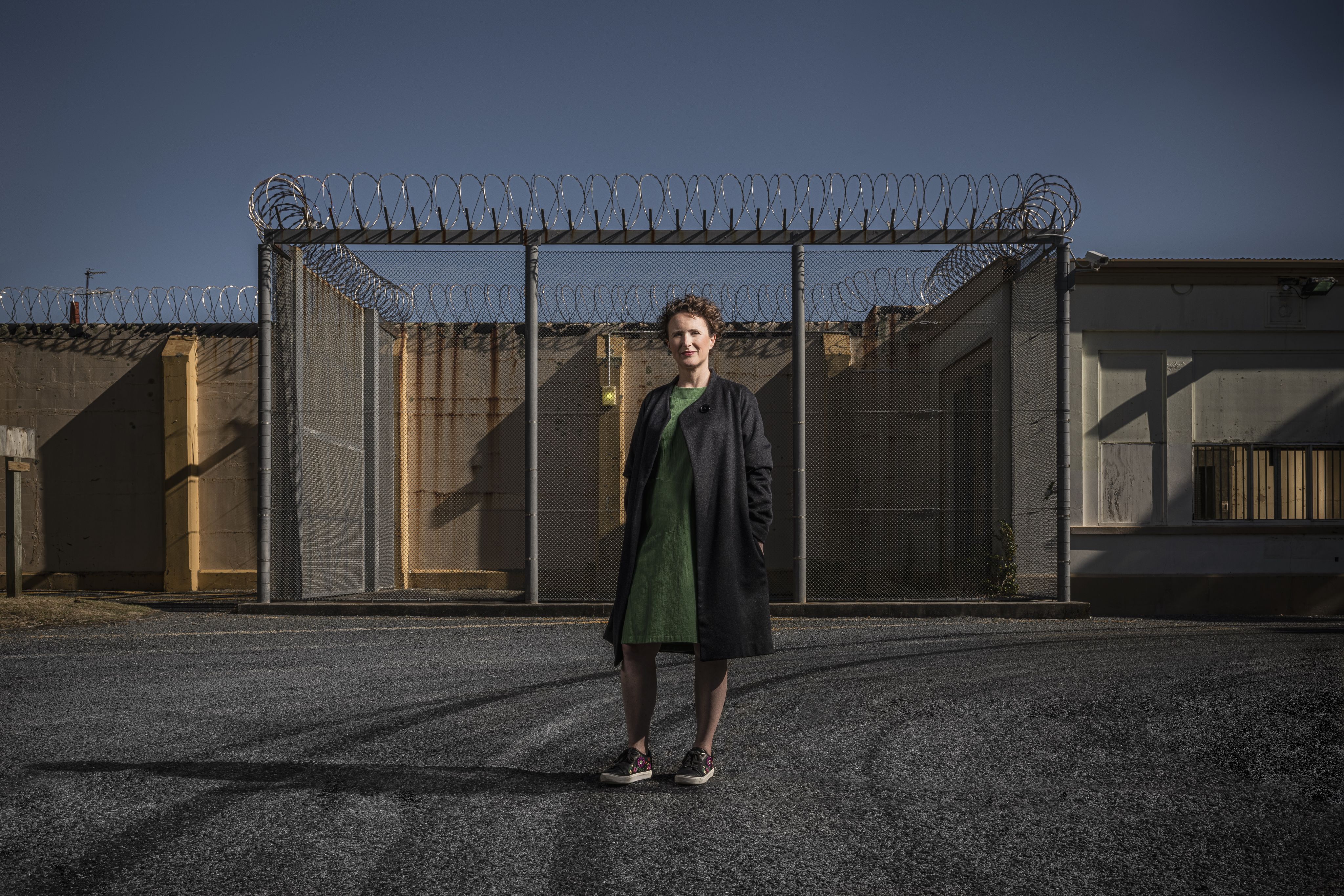Professor Elizabeth Stanley standing in front of a barbed wire fence at a prison 