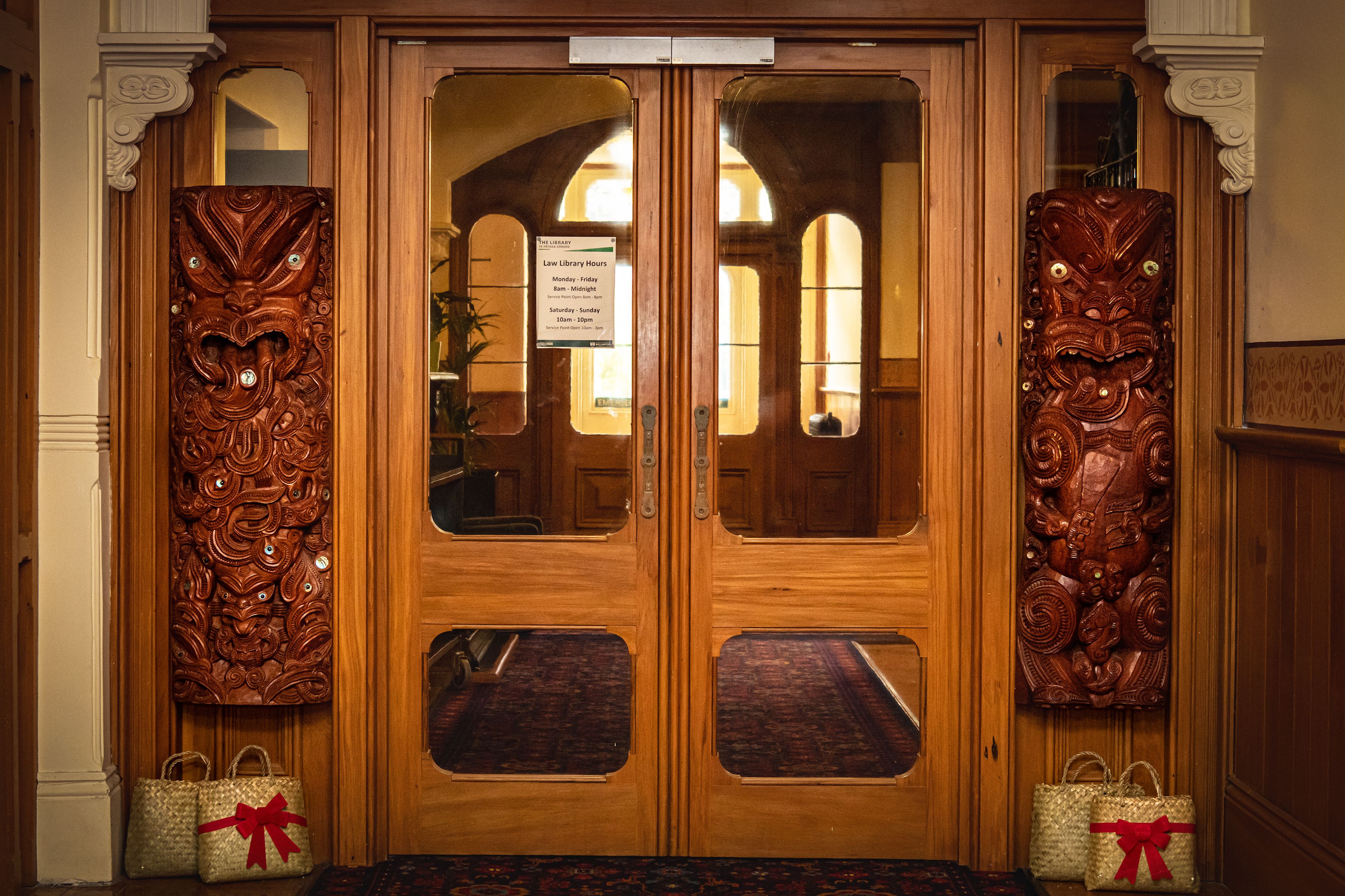 Two carved pou guarding the law library, with parcels of presents below them in flax bags